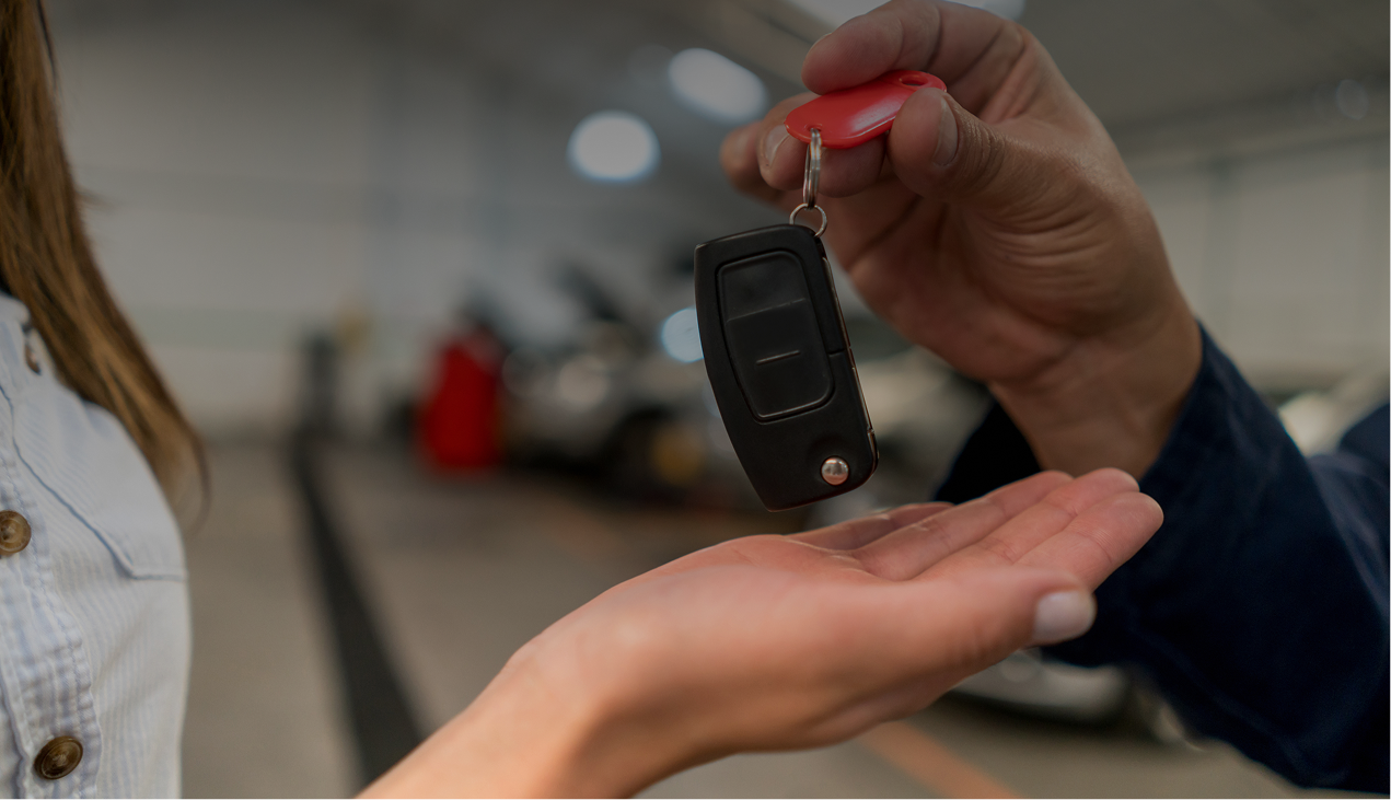 Hand receiving car key in dealership.